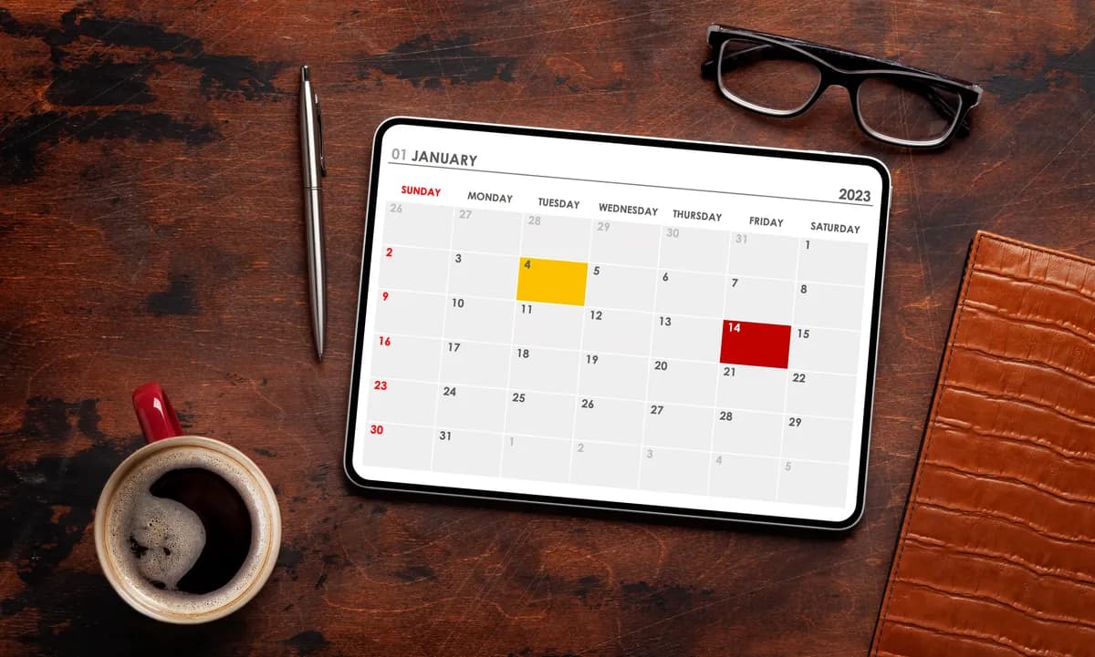 A tablet showing a booking calendar app next to a coffee cup